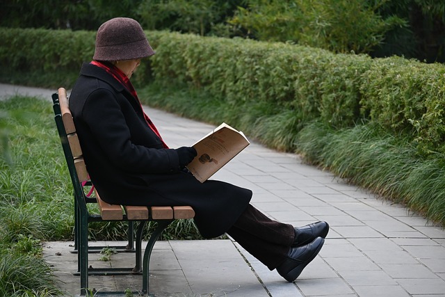 man reading a book on a bench