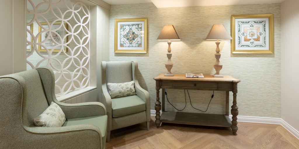 2 comfortable armchairs and table with lamps on