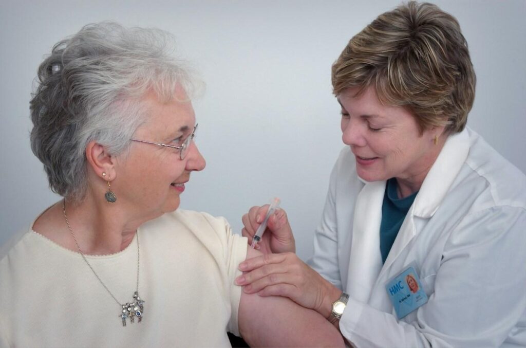 nurse in a care home giving a female resident a vaccine injection