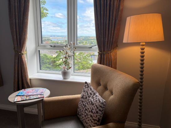 A tastefully decorated private bedroom at Highwood Care Home with a wide window view
